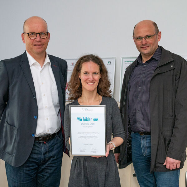 Bernhard Schmid, Stefanie Bauer und Manuel Forero Sanchez von SRL Dental halten stolz eine Ausbildungsurkunde 