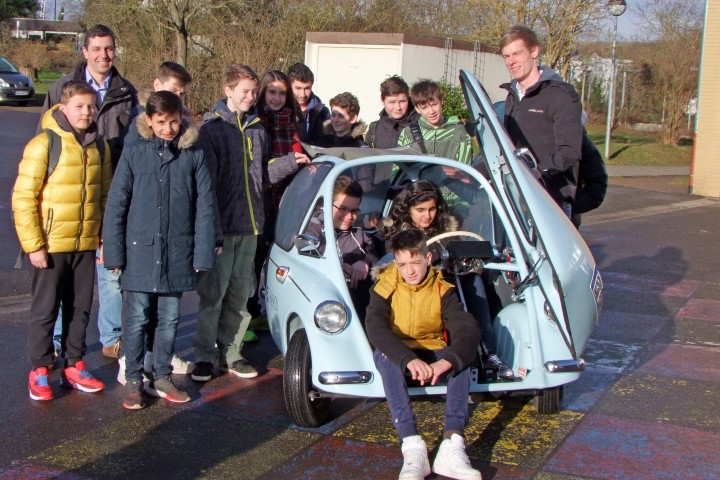 Probesitzen im E-Auto: Nach dem Workshop mit Michelin Ausbilder Michael Schwab (2. v. l.) erläuterte RWE-Projektmitarbeiter Tobias Post (r.) den Schülerinnen und Schülern am umgebauten Heinkel die praktische Seite der Elektromobilität.